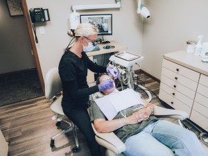 Dental hygienist treating patient in exam chair