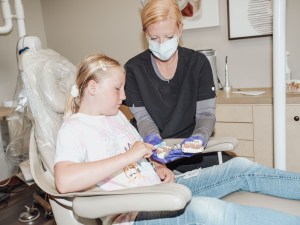 Dental assistant treating young patient in chair