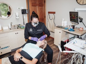 Hygienist performing procedure on patient with mask and gloves