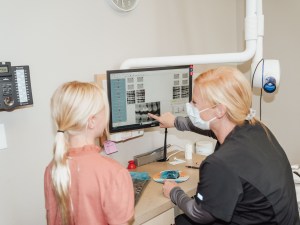 Dentist showing X-rays to child patient on digital screen
